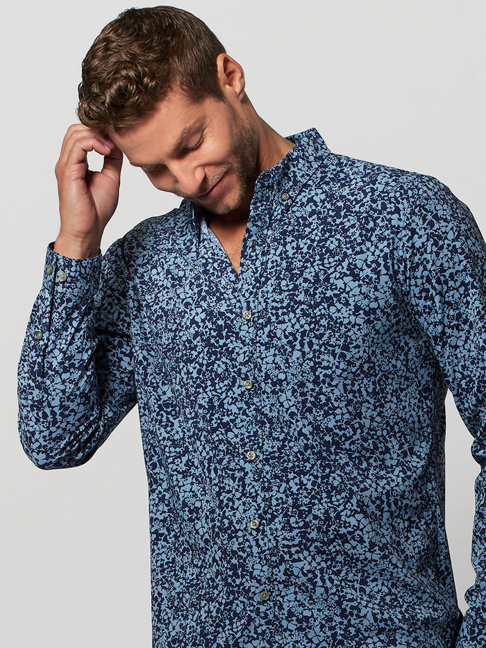 Blue Floralia-pattern long-sleeve shirt, front view, man looking down, touching head.