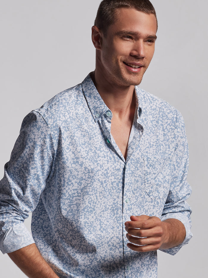 Light blue and white floral-print long-sleeve shirt, front view on smiling man against plain light background.