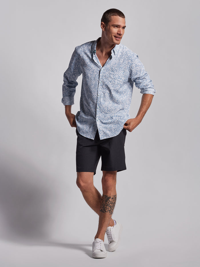 Blue floral-print long-sleeve shirt, front view, with black shorts and white sneakers.