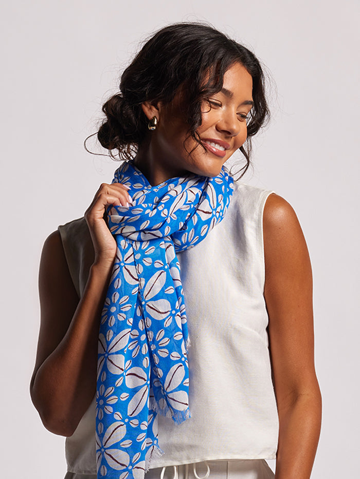 Blue woodblock-print Flowrie Scarf, styled on woman, front view, plain background.