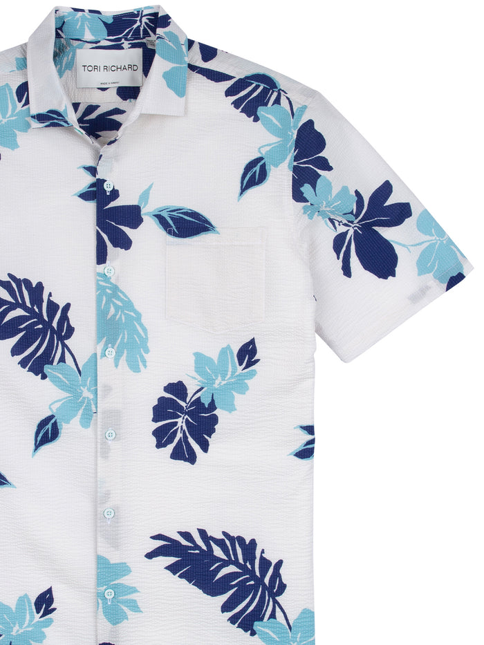 White short-sleeve crinkled cotton shirt with blue and navy tropical leaf print, front view.