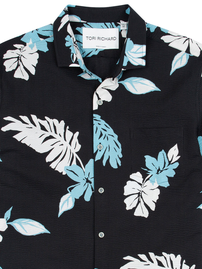 Black button-up shirt with blue and white tropical floral print, front view.