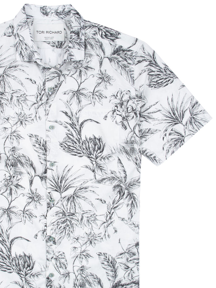 White cotton Hawaiian shirt with black floral and leaf print, chest-up view.