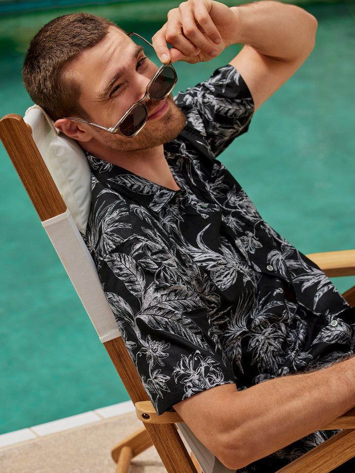 Black and cream patterned short-sleeve shirt, front view, model seated by pool