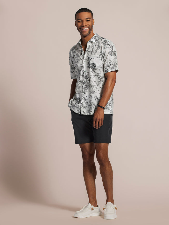 White Gingerly-print short-sleeve shirt, black shorts, and white sneakers, front view.