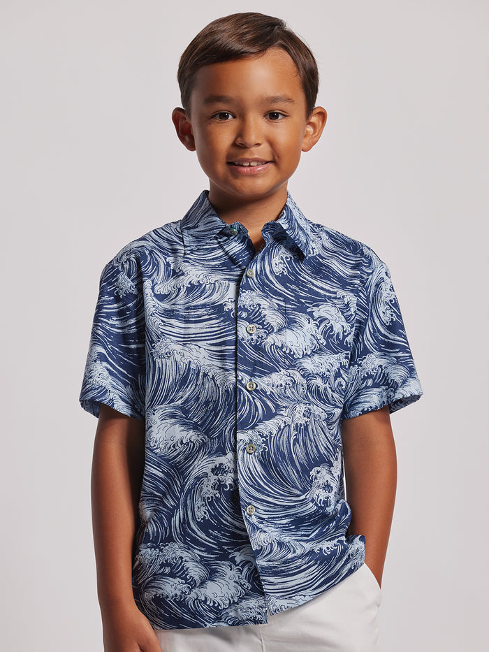 Blue wave-pattern short-sleeve shirt and white pants, front view, plain background.