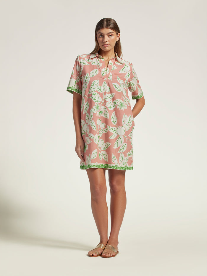 Pink floral cotton voile dress with green trim, full-length view of woman in sandals.
