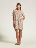 Pink floral cotton voile dress with green trim, full-length view of woman in sandals.