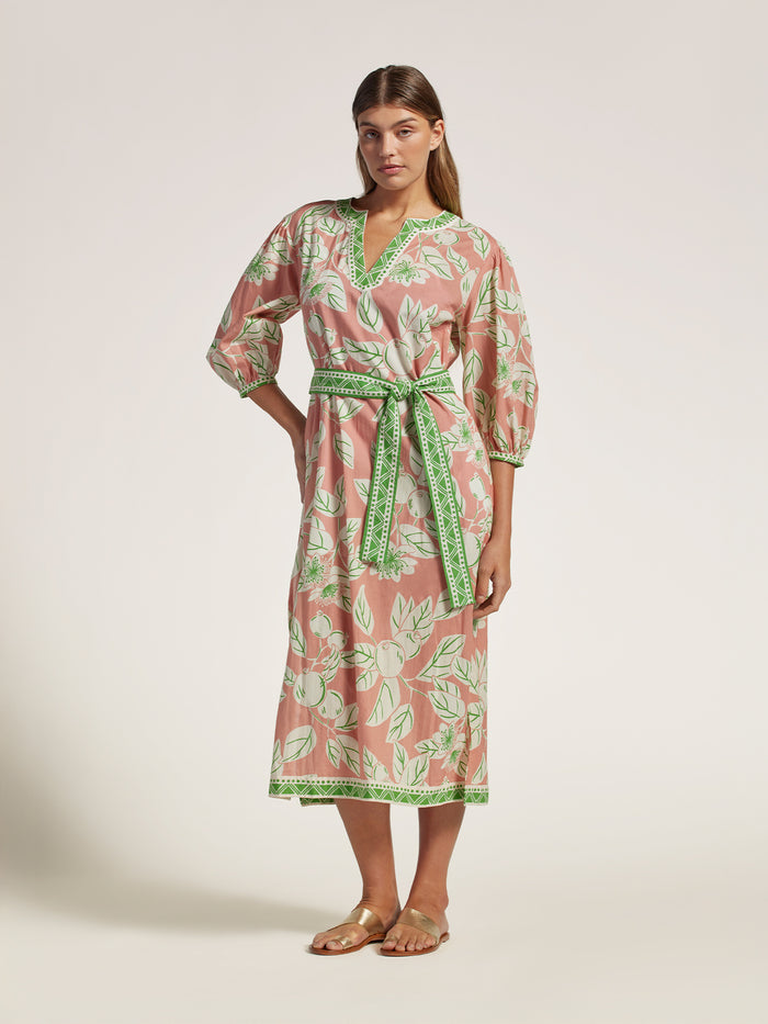 Pink floral cotton caftan dress with green trim and sash, shown on model, front view.