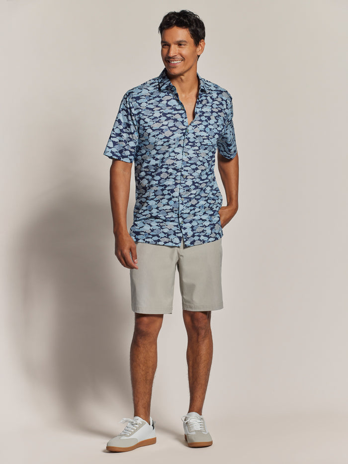 Blue Hawaiian cotton short-sleeve shirt, blue fish print, tropical-print short-sleeve shirt with light gray shorts, front view; matching set, standing front view.