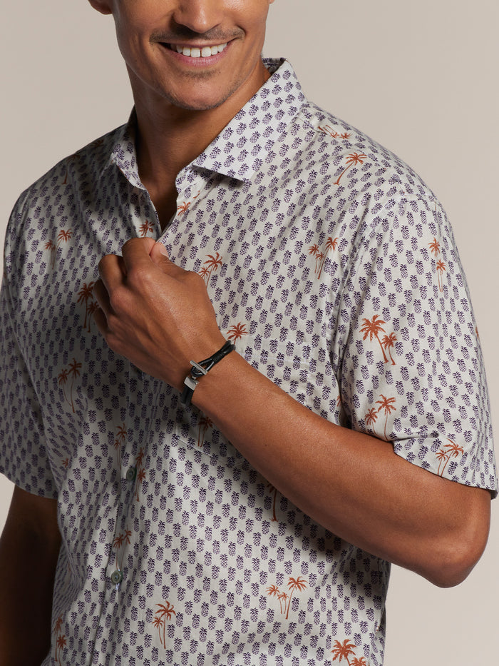 Purple and cream pineapple-print short-sleeve shirt, front view, man adjusting collar.