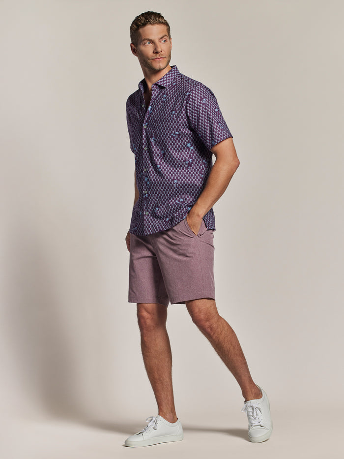 Purple palm tree and blue pineapples-print short-sleeve shirt and mauve shorts, front walking view.