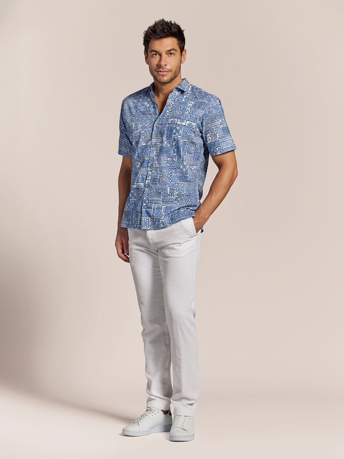 Blue aloha-print short-sleeve shirt, front view, a man with white pants and sneakers .