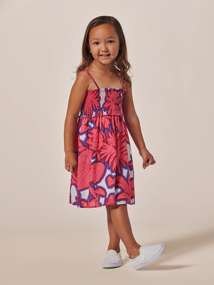 Blue and white ikat-print cotton sundress with smocked bodice, front view in both images.