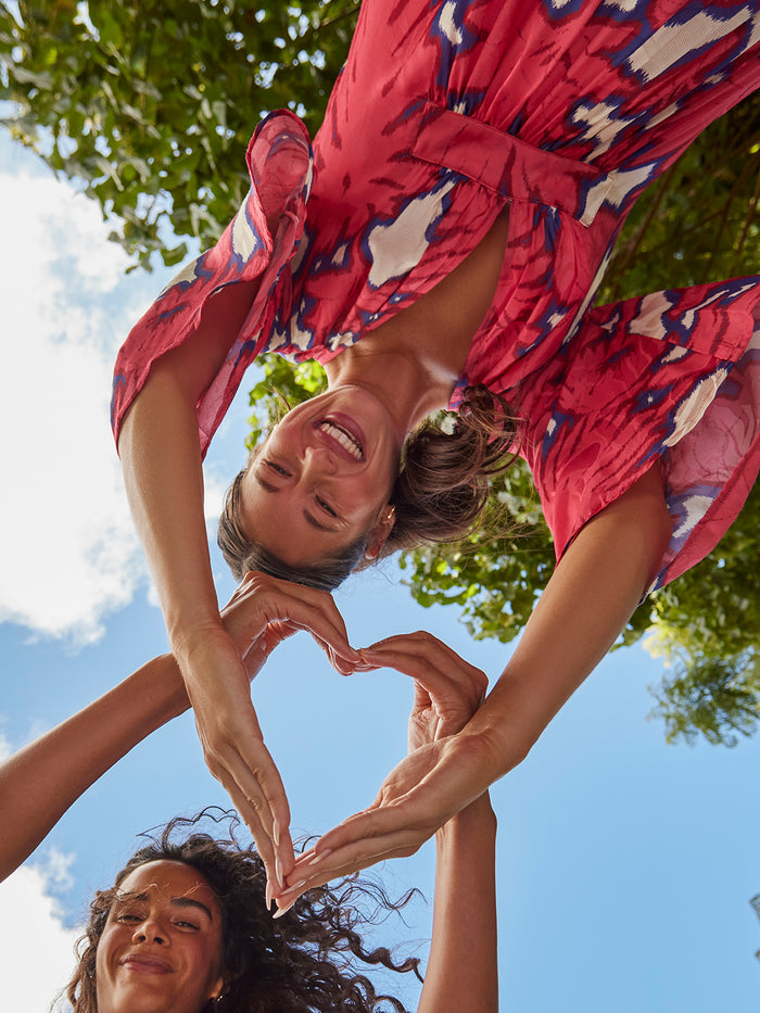 Ikat-print multicolor Roisin caftans, outdoor view with two women smiling and making a heart shape.