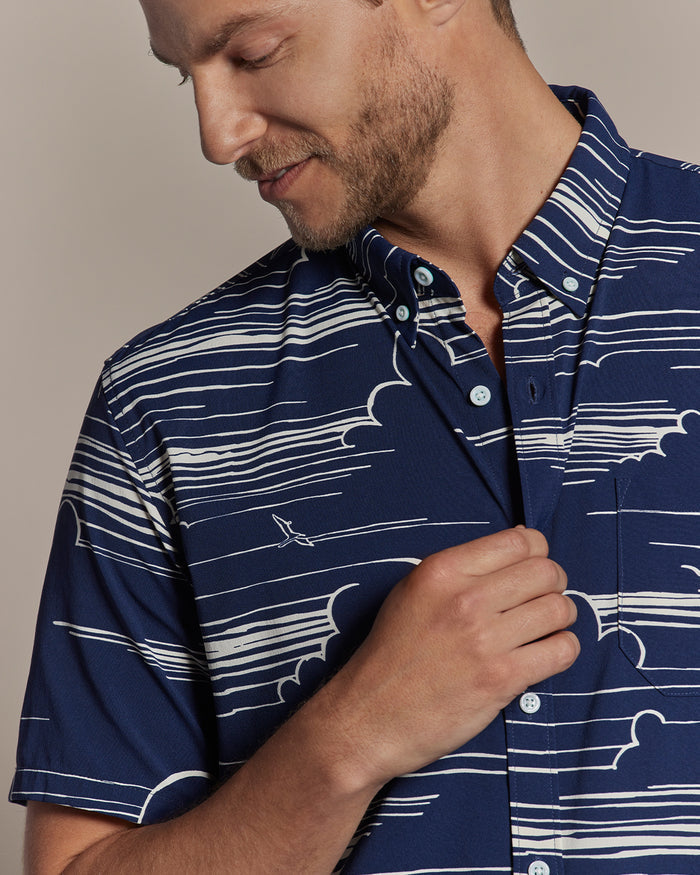 Blue shirt with white cloud and line pattern, short sleeves, model looking down, front view.