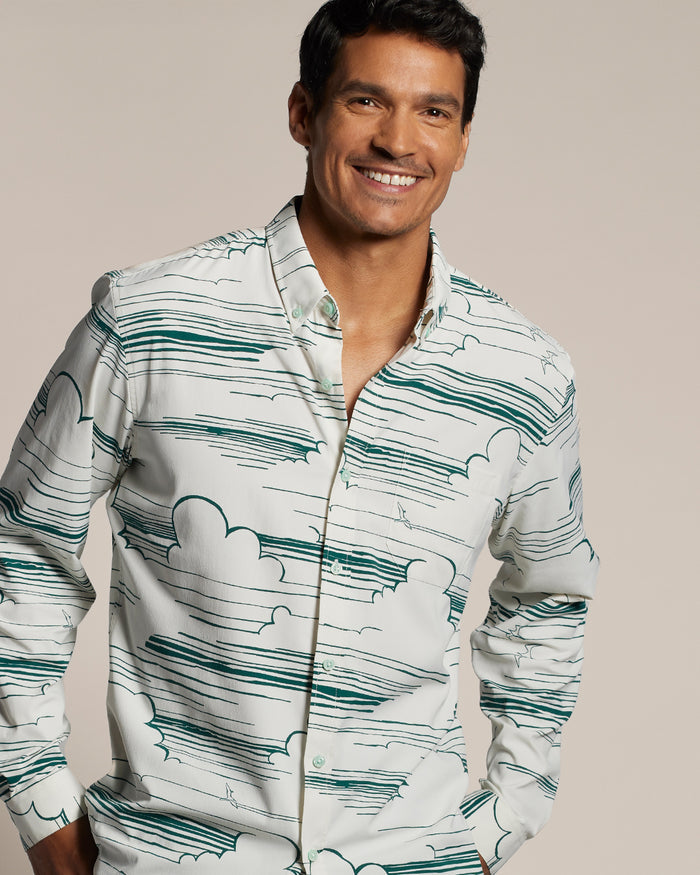 Smiling man wearing a green patterned long-sleeve shirt, front view, against neutral background.