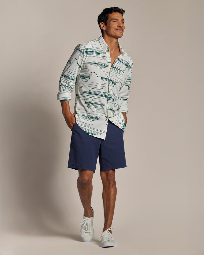 Blue long-sleeve performance shirt with navy shorts and white sneakers, front view.