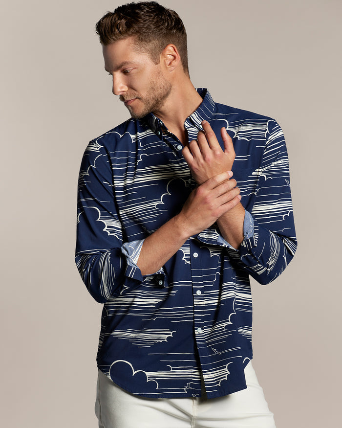 Navy and white long-sleeve performance shirt, plain background, model touching sleeve.
