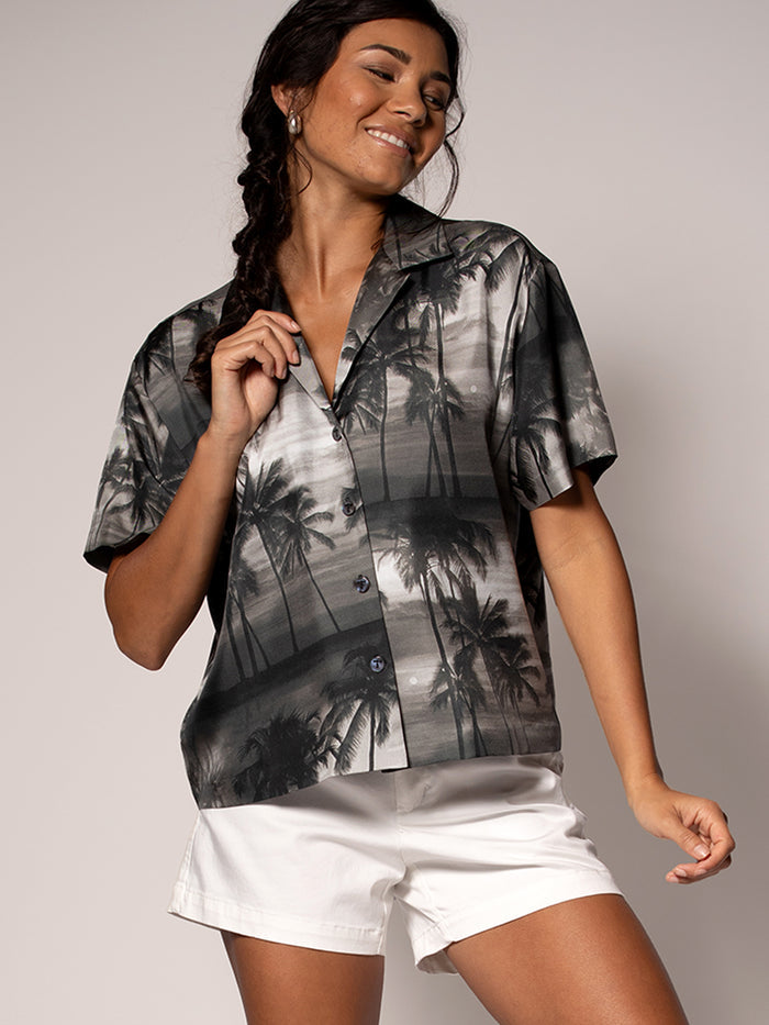 Black cabana-print sleeveless top with white shorts, front view, plain background.