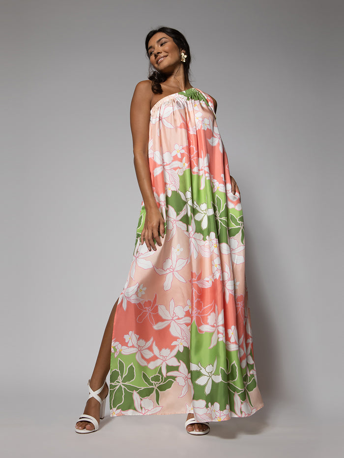 Blush pink and purple cattleya orchid-print dress, full view with model standing and smiling.