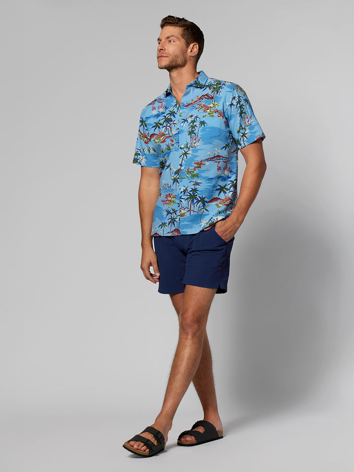 Navy blue Hawaiian-print short-sleeve shirt with navy shorts and sandals, front view.