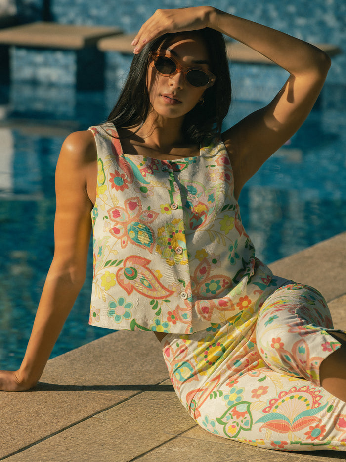 Pastel patterned Alia top and skirt, woman seated poolside with sunglasses, front view.