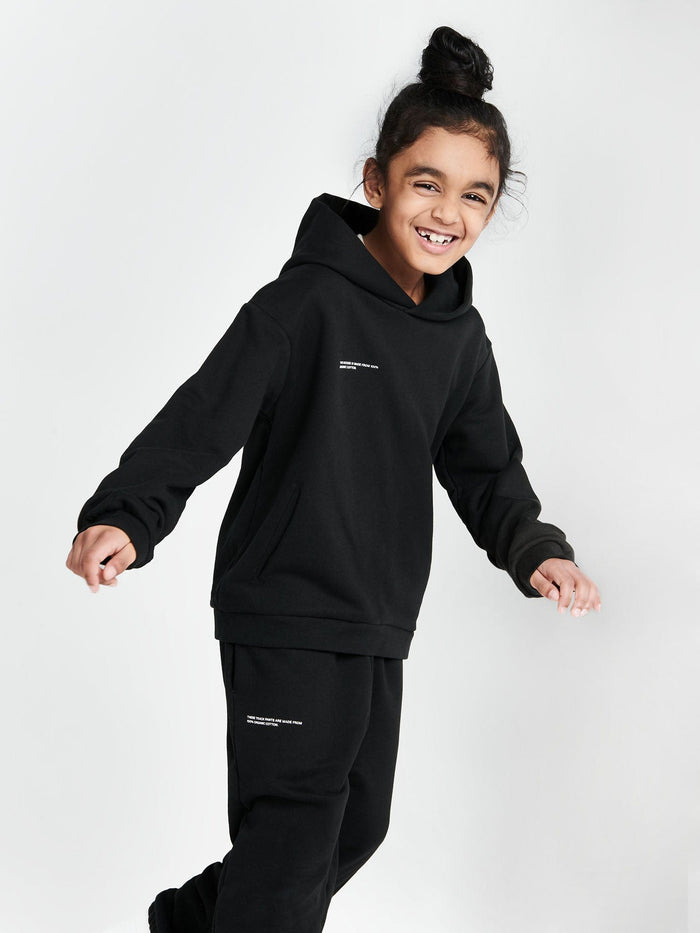 Smiling child wearing black Kids' 365 Midweight Hoodie. 320 GSM organic cotton, boxy oversized fit, hood, kangaroo pocket