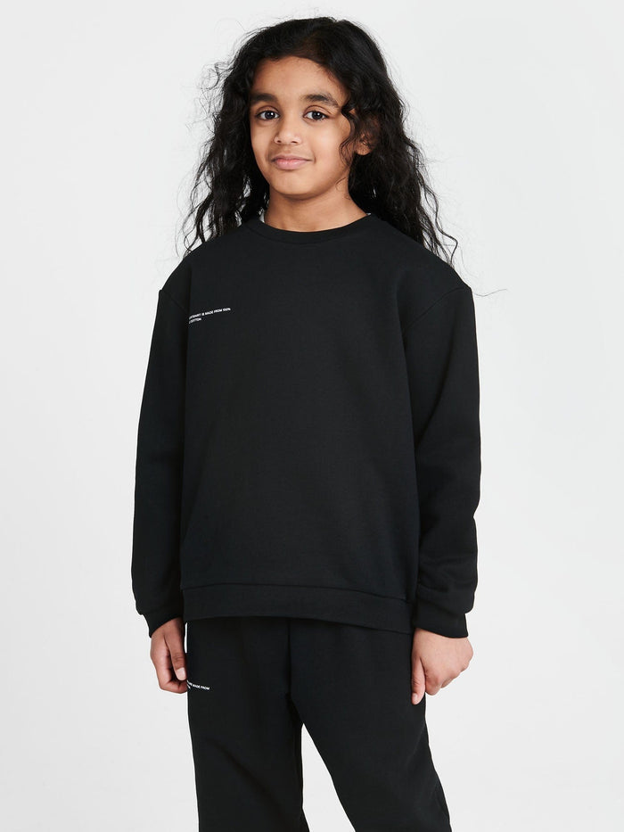 Child wears black 365 Midweight 320 GSM organic cotton sweatshirt, oversized fit, crew neck, genderless design