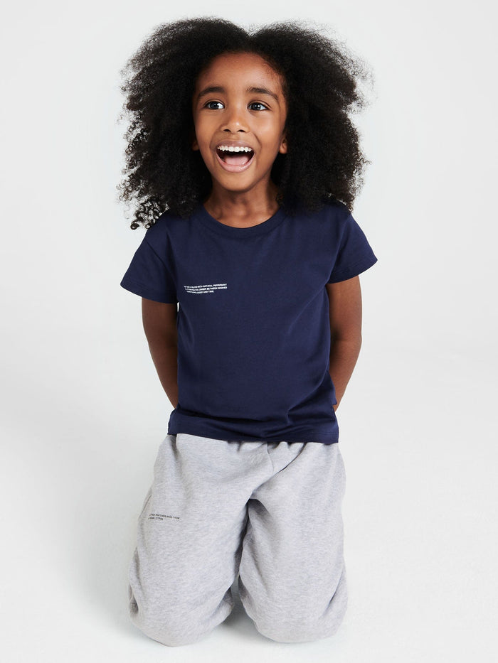 Smiling child wears navy Kids' 365 Midweight T-shirt with oversized 320 GSM organic cotton, crew neck, short sleeve