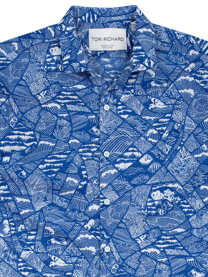 Navy and white tropical leaf, wave-mosaic print short-sleeve button-up shirt front view. Close-up of fabric pattern.