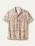 Beige short-sleeve button-up shirt with brown geometric tribal pattern, front view.