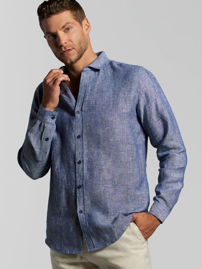 Blue solid linen long-sleeve shirt paired with beige pants, worn by a model in a front view with one hand in a pocket.