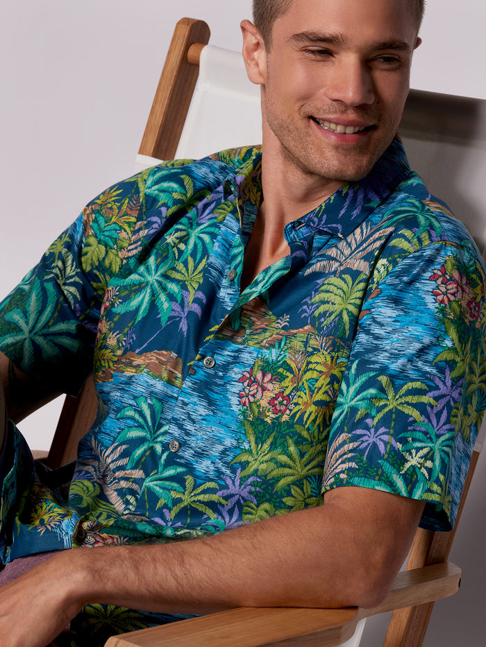 Blue and white map-print cotton short-sleeve shirt, front view, worn by seated man.