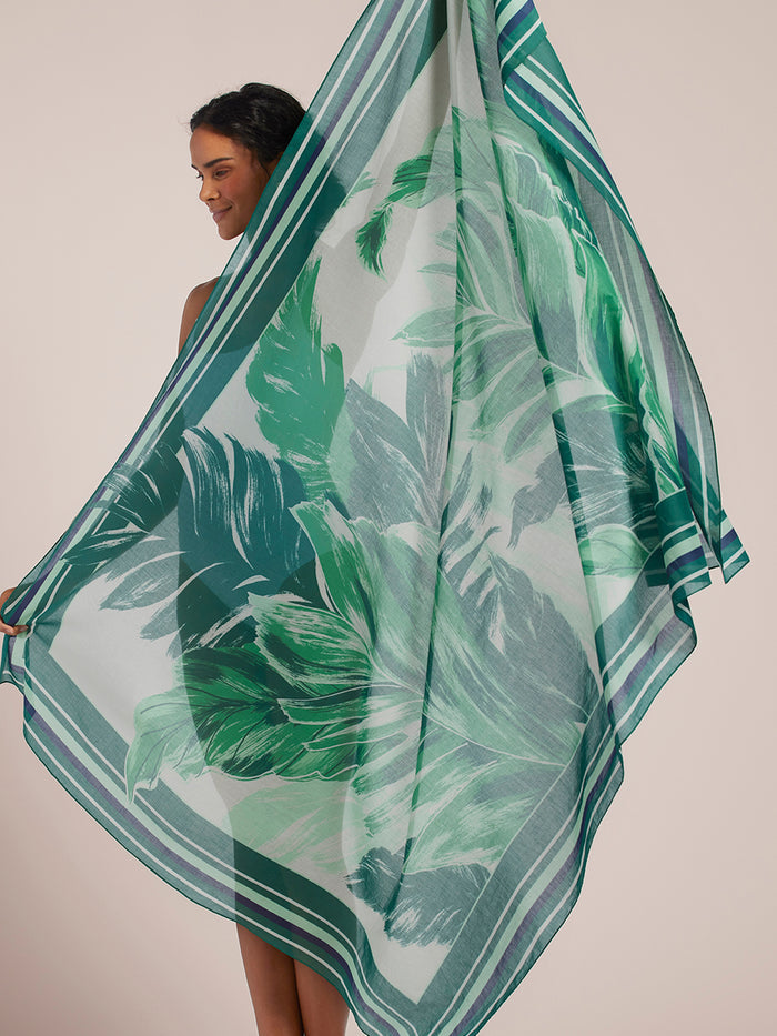 Green leaf-print sheer cotton pareo scarf with striped borders, shown from front and angled views.