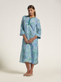 Woman wearing a blue-green patterned dress on a white background
