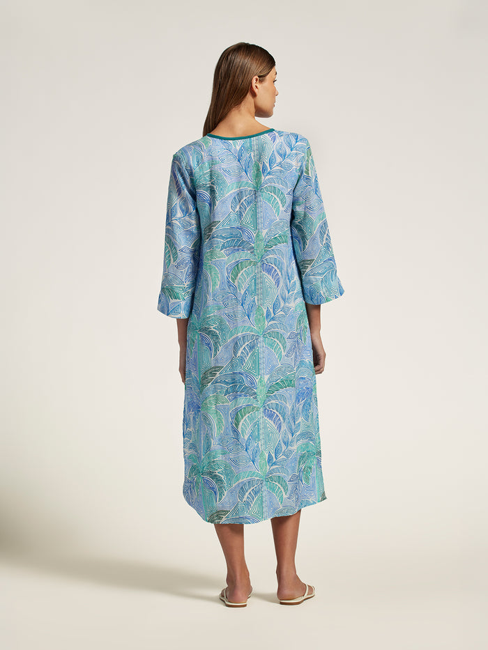 Woman wearing a blue patterned dress on a plain background