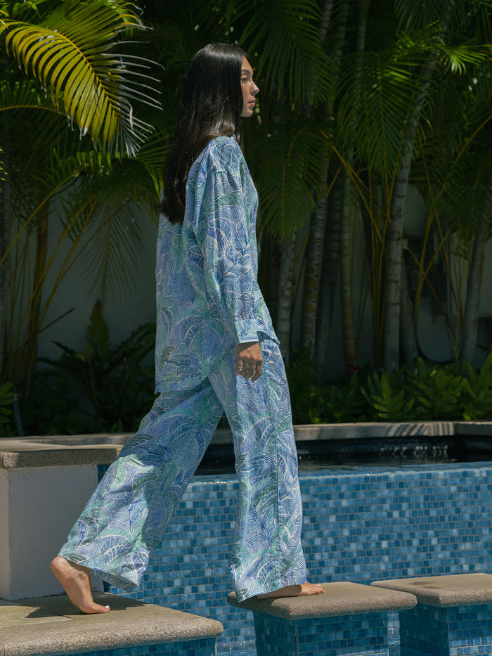 Loose light blue and white tropical print lounge set with a matching head covering in a tropical garden setting.