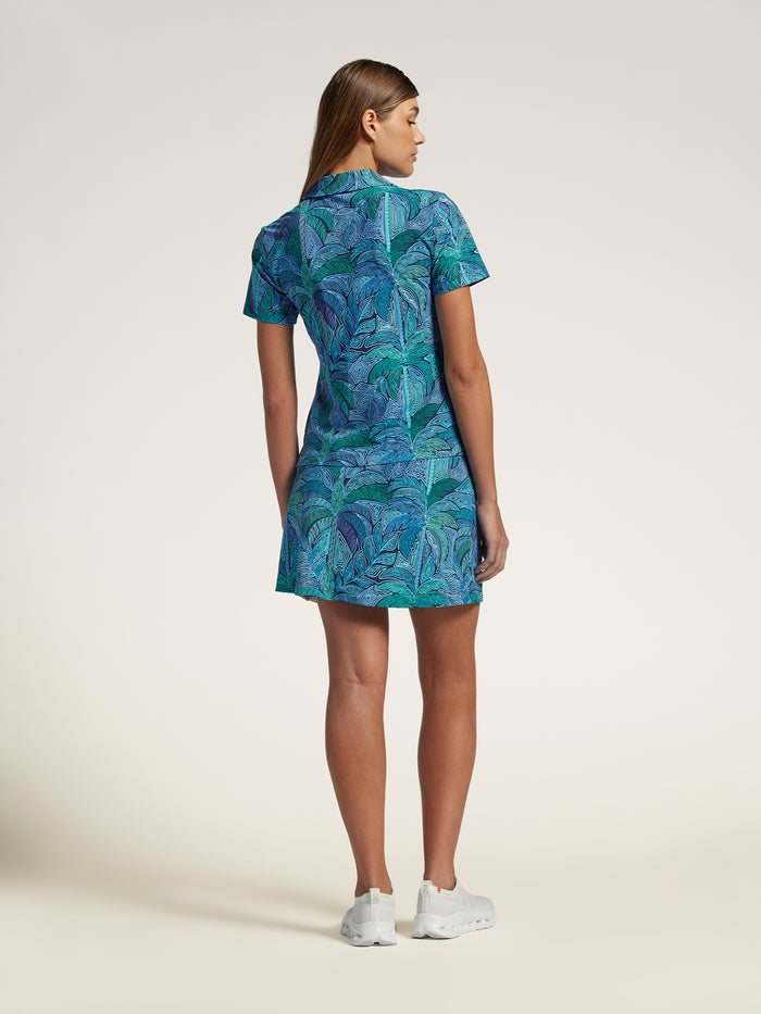 Blue-green leaf print polo shirt, back view, worn with white sneakers.