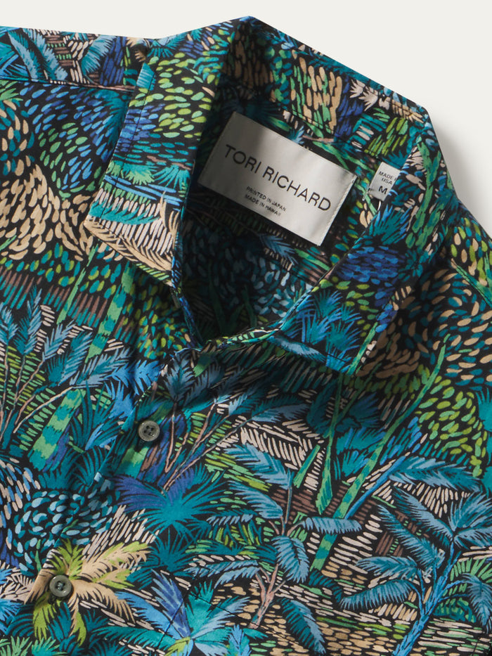 Green and blue tropical-leaf print cotton shirt, fabric detail close-up.