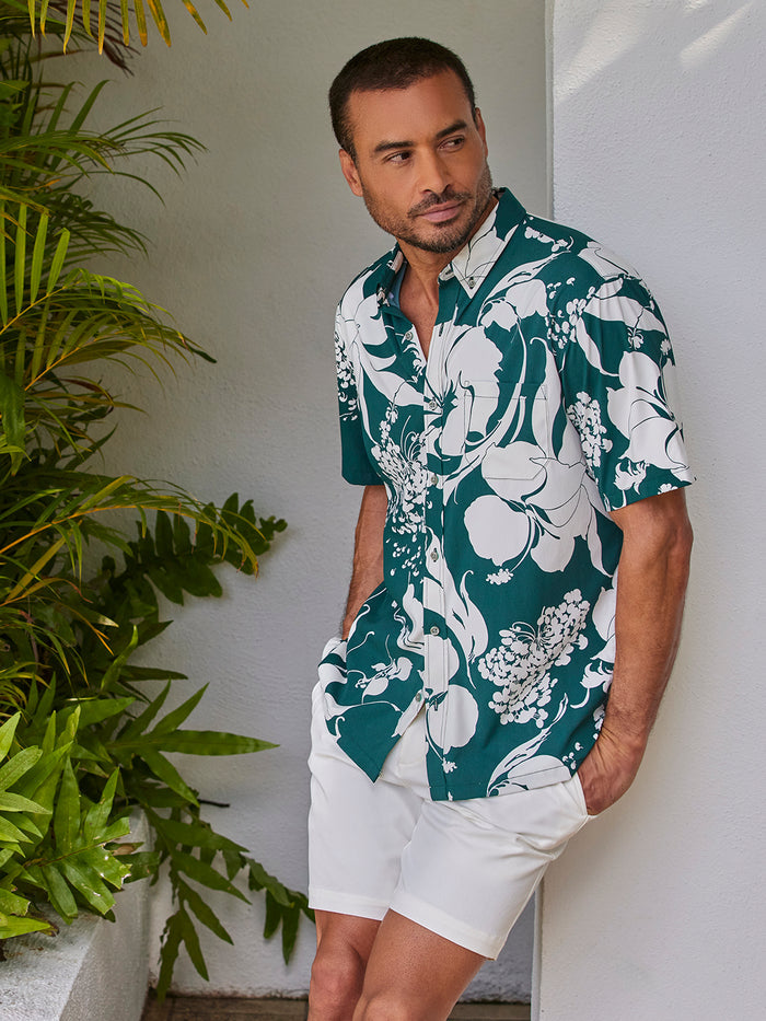 Green floral-print UPF short-sleeve shirt, side view by tropical plants.
