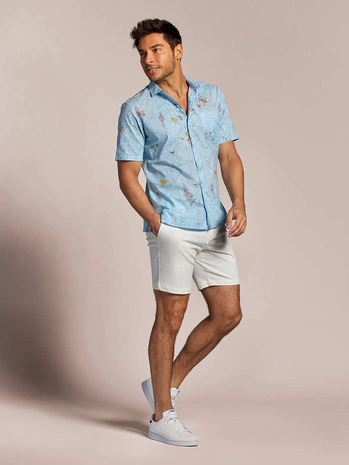 Light blue short-sleeve Hawaiian shirt with orange and red floral print short sleeve shirt and white shorts, front view.