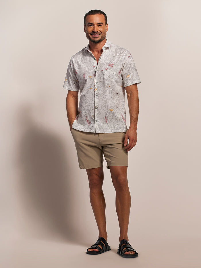 Beige tropical-print short-sleeve cotton shirt, khaki shorts, and black sandals, front view of a male model.