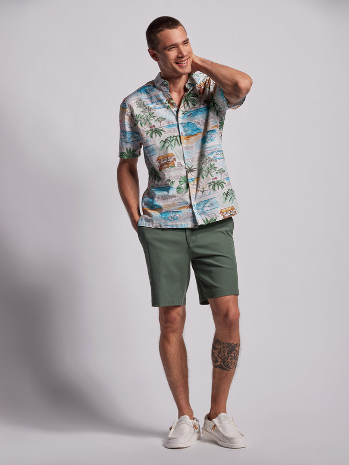 White and green tropical-print short-sleeve shirt, man smiling from the front view.