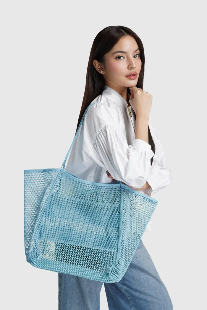 woman carrying mesh tote bag ocean by buttonscarves