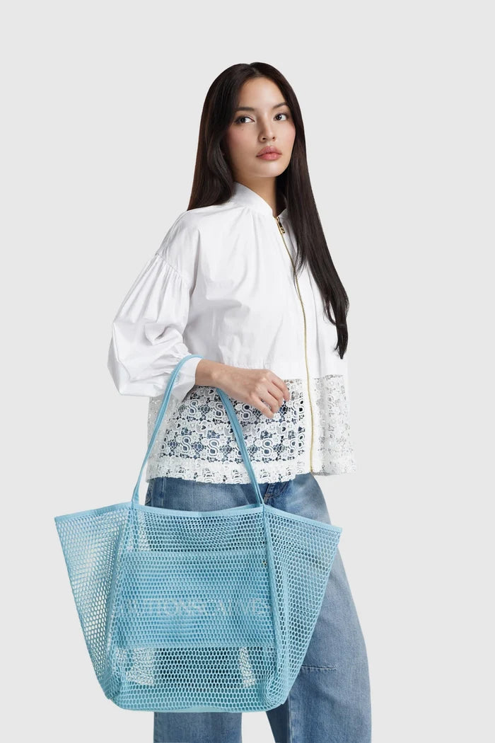 woman carrying mesh tote bag ocean by buttonscarves