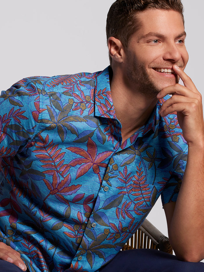 Blue and white moire floral cotton short-sleeve shirt, seated front view, relaxed pose.