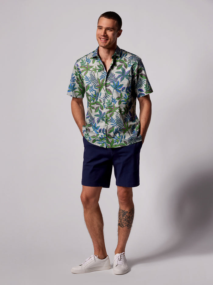 Navy/gray moiré-print short-sleeve shirt with navy shorts, front view and with hands in pockets, front view.