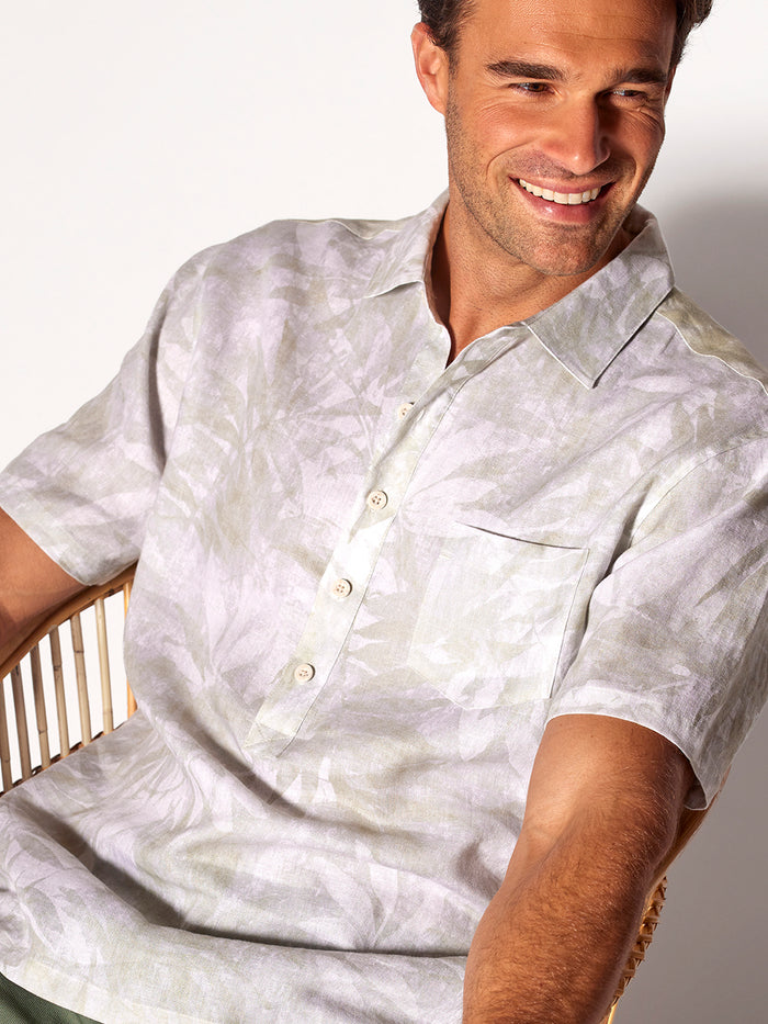 White monochrome half-placket shirt, seated front view, palm leaves in background (Images 1 & 2).