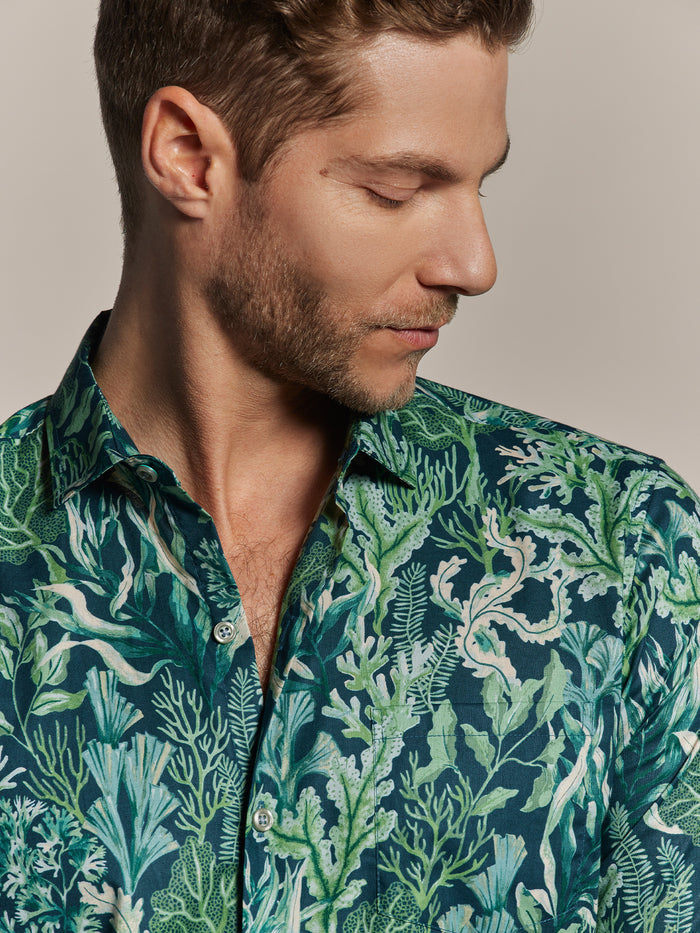 Green and white Neptune’s Garden print short-sleeve shirt, model looking down, front view.